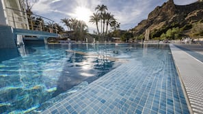 Una piscina cubierta, una piscina al aire libre, sombrillas, tumbonas