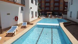 Una piscina al aire libre, tumbonas