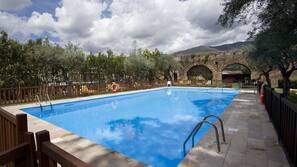 Una piscina al aire libre de temporada, sombrillas
