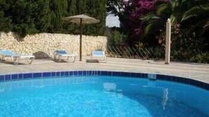 Una piscina al aire libre, sombrillas, tumbonas