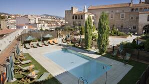 Una piscina al aire libre de temporada, sombrillas, tumbonas