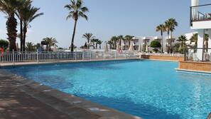 Una piscina al aire libre, sombrillas, tumbonas