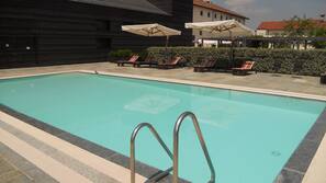 Una piscina cubierta, una piscina al aire libre, sombrillas, tumbonas