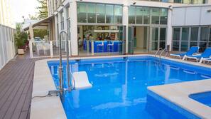 Una piscina al aire libre, sombrillas, tumbonas