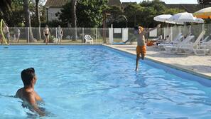 Una piscina al aire libre, sombrillas, tumbonas