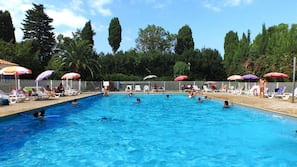 Una piscina al aire libre, sombrillas, tumbonas