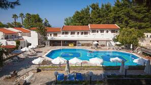 Una piscina al aire libre, sombrillas, tumbonas