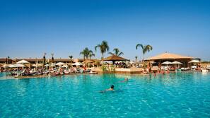 Una piscina cubierta, una piscina al aire libre, sombrillas, tumbonas
