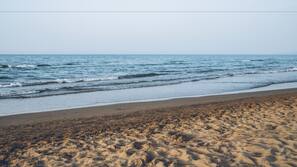Aan het strand, wit zand, ligstoelen aan het strand, parasols