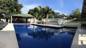 Una piscina al aire libre, sombrillas, tumbonas