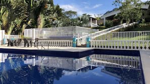 Una piscina al aire libre, sombrillas, tumbonas