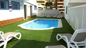 Una piscina al aire libre de temporada, sombrillas, tumbonas