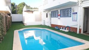 Una piscina al aire libre de temporada, sombrillas, tumbonas