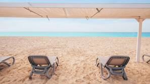 Privéstrand vlakbij, wit zand, ligstoelen aan het strand, parasols