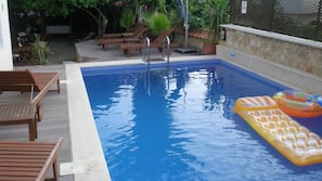 Una piscina al aire libre de temporada, sombrillas, tumbonas