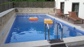 Una piscina al aire libre de temporada, sombrillas, tumbonas