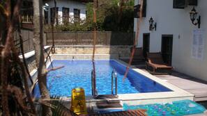 Una piscina al aire libre de temporada, sombrillas, tumbonas