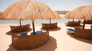 Een privéstrand, ligstoelen aan het strand, parasols, strandlakens