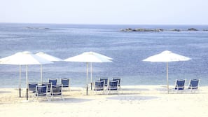 Am Strand, weißer Sandstrand, Liegestühle, Sonnenschirme