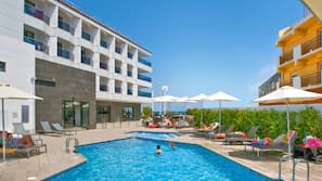 Una piscina al aire libre, sombrillas, tumbonas
