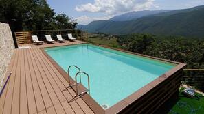 Una piscina al aire libre de temporada, tumbonas