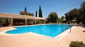 Una piscina al aire libre, sombrillas, tumbonas