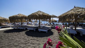On the beach, black sand, sun-loungers, beach umbrellas