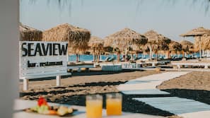 On the beach, black sand, sun-loungers, beach umbrellas