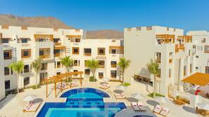 Una piscina al aire libre, sombrillas, tumbonas