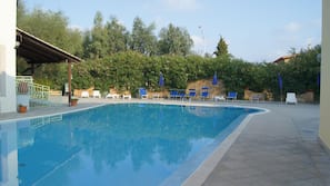 Una piscina al aire libre, sombrillas, tumbonas