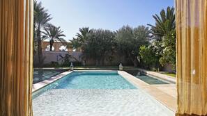 Una piscina al aire libre, sombrillas, tumbonas