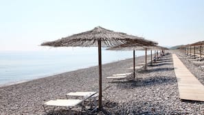 Een privéstrand, ligstoelen aan het strand, parasols, strandlakens