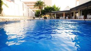Una piscina cubierta, una piscina al aire libre, sombrillas, tumbonas