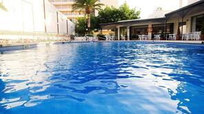Una piscina cubierta, una piscina al aire libre, sombrillas, tumbonas
