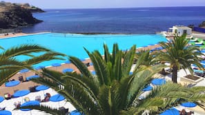 Una piscina al aire libre, sombrillas, tumbonas