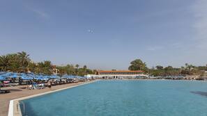 Una piscina al aire libre, sombrillas, tumbonas