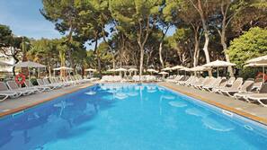 Una piscina al aire libre, sombrillas, tumbonas