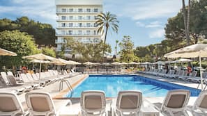 Una piscina al aire libre, sombrillas, tumbonas