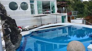 Una piscina al aire libre, sombrillas, tumbonas