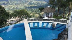 Una piscina al aire libre, sombrillas, tumbonas