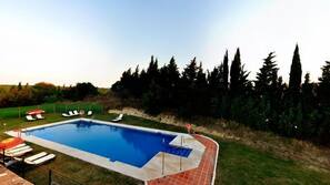 Una piscina al aire libre, sombrillas, tumbonas