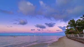 Na praia, areia branca, barracas de praia de cortesia, espreguiçadeiras