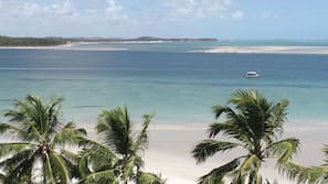 Na praia, areia branca, barracas de praia de cortesia, espreguiçadeiras