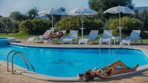 Una piscina al aire libre de temporada, sombrillas, tumbonas