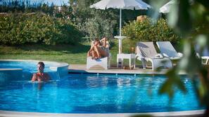 Una piscina al aire libre de temporada, sombrillas, tumbonas