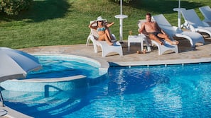 Una piscina al aire libre de temporada, sombrillas, tumbonas