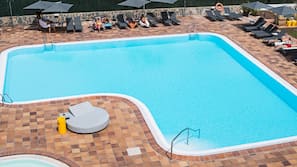 Een buitenzwembad, parasols voor strand/zwembad