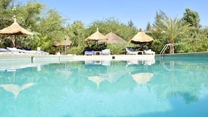 Una piscina al aire libre, sombrillas, tumbonas