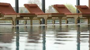 Een binnenzwembad, een buitenzwembad, ligstoelen bij het zwembad