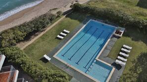Una piscina al aire libre de temporada, sombrillas, tumbonas